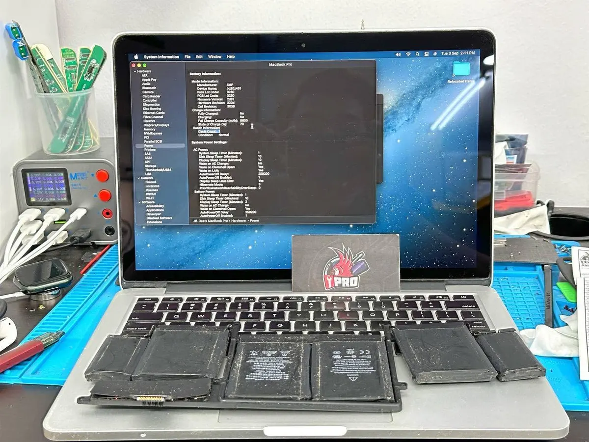 Old MacBook Pro battery cells laid out in front of the Mac during a battery replacement